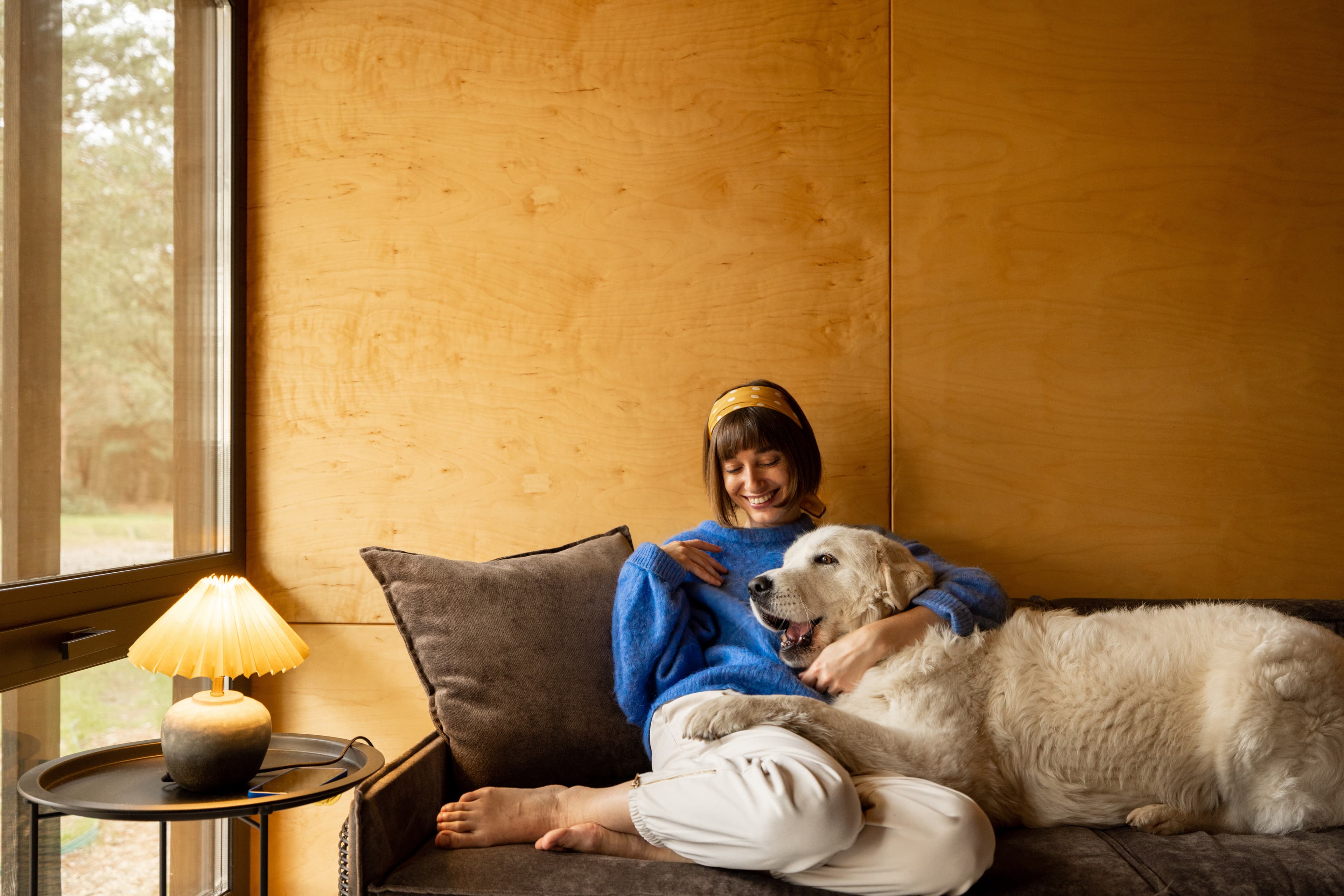 Woman relaxing on couch with her dog in a warm, comfortable home